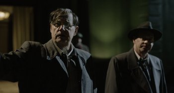Movie still from “The Death of Stalin” (2017), directed by Armando Iannucci – An older man wearing glasses and a jacket; Medium shot, Over the shoulder angle
