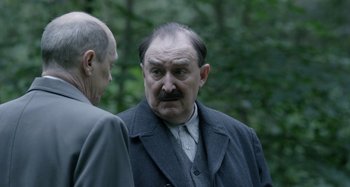 Movie still from “The Death of Stalin” (2017), directed by Armando Iannucci – A man with a beard and mustache and a suit; Close Up shot, Over the shoulder angle