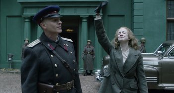 Movie still from “The Death of Stalin” (2017), directed by Armando Iannucci – A man and a woman in military garb are standing in front of a building; Medium shot, Low angle