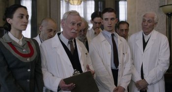 Movie still from “The Death of Stalin” (2017), directed by Armando Iannucci – A group of men in white lab coats standing next to each other; Medium shot, Over the shoulder angle