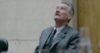 Movie still from “The Death of Stalin” (2017), directed by Armando Iannucci – An older man wearing a suit and tie; Close Up shot, Over the shoulder angle
