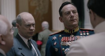 Movie still from “The Death of Stalin” (2017), directed by Armando Iannucci – A man in a suit standing next to another man in a uniform; Close Up shot, Over the shoulder angle