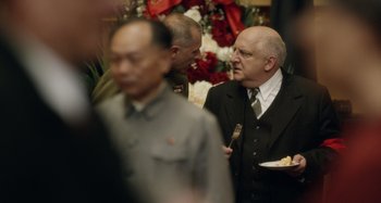 Movie still from “The Death of Stalin” (2017), directed by Armando Iannucci – A man in a suit and tie standing next to another man in a suit and tie; Medium shot, Over the shoulder angle