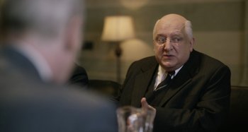 Movie still from “The Death of Stalin” (2017), directed by Armando Iannucci – An older man wearing a suit and tie; Close Up shot, Over the shoulder angle