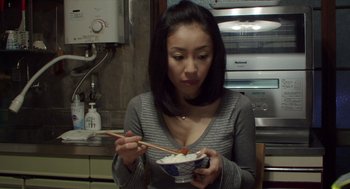 Movie still from “Cold Fish” (2010), directed by Sion Sono – A woman holding chopsticks over a bowl of rice; Close Up shot, High angle