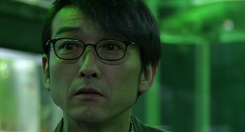 Movie still from “Cold Fish” (2010), directed by Sion Sono – A person wearing glasses; Close Up shot, Low angle