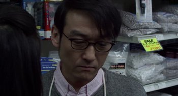 Movie still from “Cold Fish” (2010), directed by Sion Sono – A person wearing glasses and a sweater; Close Up shot, Low angle