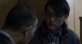 Movie still from “Cold Fish” (2010), directed by Sion Sono – A man with glasses is talking to another man; Close Up shot, Over the shoulder angle