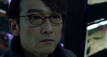 Movie still from “Cold Fish” (2010), directed by Sion Sono – A person wearing glasses; Close Up shot, Over the shoulder angle
