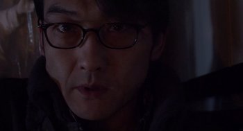 Movie still from “Cold Fish” (2010), directed by Sion Sono – A person wearing glasses; Close Up shot, Over the shoulder angle