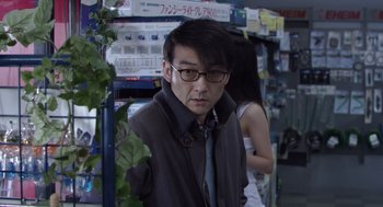 Movie still from “Cold Fish” (2010), directed by Sion Sono – A man wearing glasses and a jacket and a tie; Close Up shot, Over the shoulder angle
