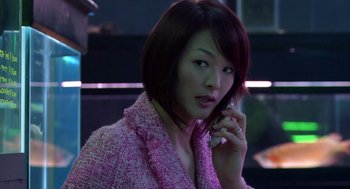 Movie still from “Cold Fish” (2010), directed by Sion Sono – A woman talking on a cell phone while wearing a pink jacket; Close Up shot, Over the shoulder angle
