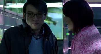 Movie still from “Cold Fish” (2010), directed by Sion Sono – A man and a woman standing next to each other in front of a fish tank; Close Up shot, Over the shoulder angle