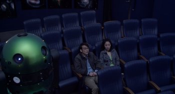 Movie still from “Cold Fish” (2010), directed by Sion Sono – A man and a woman sitting in a movie theater; Wide shot, High angle