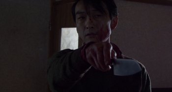 Movie still from “Cold Fish” (2010), directed by Sion Sono – A man holding a knife in a dark room; Close Up shot, Low angle