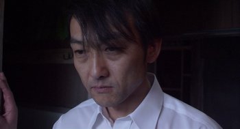 Movie still from “Cold Fish” (2010), directed by Sion Sono – A person wearing a white shirt; Close Up shot, Low angle