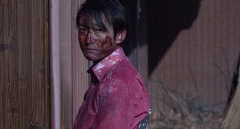 Movie still from “Cold Fish” (2010), directed by Sion Sono – A man with blood all over his face; Medium shot, Over the shoulder angle