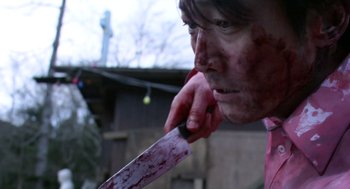Movie still from “Cold Fish” (2010), directed by Sion Sono – A man with a knife in his mouth; Close Up shot, Low angle