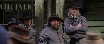 Movie still from “Cold Mountain” (2003), directed by Anthony Minghella – A group of people wearing hats in front of a building; Medium shot, Low angle