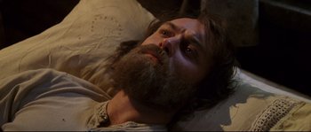 Movie still from “Cold Mountain” (2003), directed by Anthony Minghella – A man with a beard laying in a bed; Close Up shot, High angle