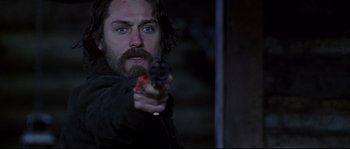 Movie still from “Cold Mountain” (2003), directed by Anthony Minghella – A man with a beard holding a gun in his hand; Close Up shot, Over the shoulder angle