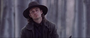 Movie still from “Cold Mountain” (2003), directed by Anthony Minghella – A man with long hair wearing a hat and a jacket; Close Up shot, Low angle