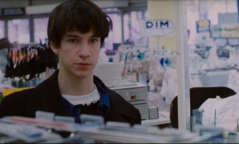 Movie still from “Cold Water” (1994), directed by Olivier Assayas – A young man is standing in front of a computer; Close Up shot, Over the shoulder angle