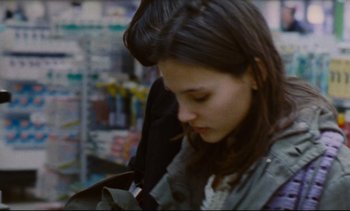 Movie still from “Cold Water” (1994), directed by Olivier Assayas – A woman holding a bag in a store; Close Up shot, Over the shoulder angle