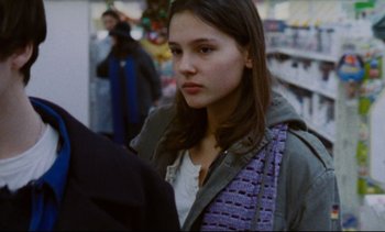 Movie still from “Cold Water” (1994), directed by Olivier Assayas – A young woman is standing in a crowd of people; Close Up shot, Over the shoulder angle
