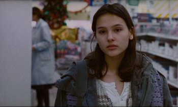 Movie still from “Cold Water” (1994), directed by Olivier Assayas – A young woman is standing in a crowded market place; Close Up shot, Over the shoulder angle
