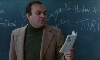 Movie still from “Cold Water” (1994), directed by Olivier Assayas – A man reading a book in front of a chalkboard; Close Up shot, Low angle