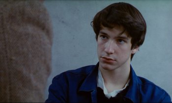 Movie still from “Cold Water” (1994), directed by Olivier Assayas – A man in a blue jacket looking at the camera; Close Up shot, Over the shoulder angle