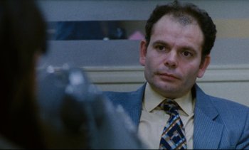 Movie still from “Cold Water” (1994), directed by Olivier Assayas – A person wearing a suit and a tie; Close Up shot, Over the shoulder angle