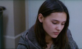 Movie still from “Cold Water” (1994), directed by Olivier Assayas – A young woman sitting in front of a wall; Close Up shot, High angle