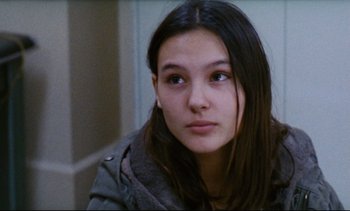 Movie still from “Cold Water” (1994), directed by Olivier Assayas – A young woman sitting in a room looking at the camera; Close Up shot, Low angle