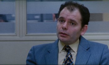 Movie still from “Cold Water” (1994), directed by Olivier Assayas – A person wearing a suit and a tie; Close Up shot, Over the shoulder angle