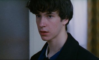 Movie still from “Cold Water” (1994), directed by Olivier Assayas – A young man in a black jacket is looking at the camera; Close Up shot, Over the shoulder angle
