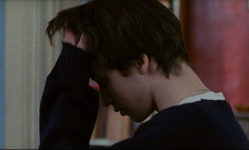 Movie still from “Cold Water” (1994), directed by Olivier Assayas – A young man is holding his head in his hands; Close Up shot, Over the shoulder angle