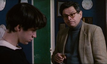 Movie still from “Cold Water” (1994), directed by Olivier Assayas – A man and a boy standing next to each other in a room; Medium shot, Over the shoulder angle