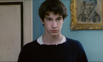 Movie still from “Cold Water” (1994), directed by Olivier Assayas – A young man in front of a blue wall; Close Up shot, Over the shoulder angle