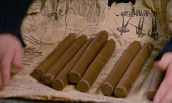 Movie still from “Cold Water” (1994), directed by Olivier Assayas – A bunch of cigars sitting on top of a newspaper; Extreme Close Up shot, Overhead angle