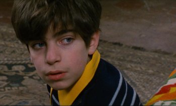 Movie still from “Cold Water” (1994), directed by Olivier Assayas – A young boy wearing a yellow and black striped shirt; Close Up shot, High angle