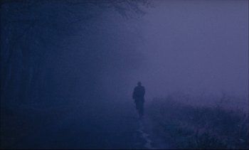 Movie still from “Cold Water” (1994), directed by Olivier Assayas – A person walking down a road in the fog; Extreme Wide shot, Low angle