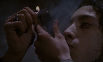 Movie still from “Cold Water” (1994), directed by Olivier Assayas – A person lighting a cigarette with a match; Extreme Close Up shot, High angle