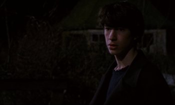 Movie still from “Cold Water” (1994), directed by Olivier Assayas – A young man is standing in the dark outside; Medium shot, Over the shoulder angle