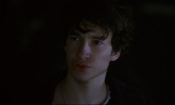 Movie still from “Cold Water” (1994), directed by Olivier Assayas – A young man with dark curly hair wearing a white shirt; Close Up shot, High angle