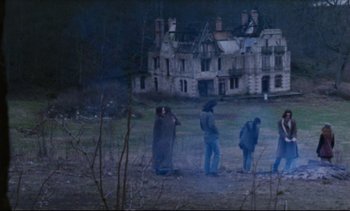 Movie still from “Cold Water” (1994), directed by Olivier Assayas – A group of people standing in front of an abandoned house; Wide shot, High angle
