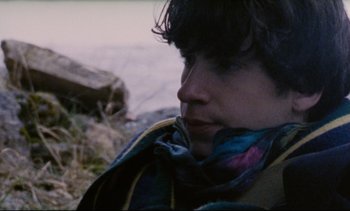 Movie still from “Cold Water” (1994), directed by Olivier Assayas – A young man with a scarf around his neck looks down; Close Up shot, High angle