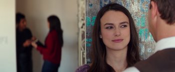 Movie still from “Collateral Beauty” (2016), directed by David Frankel – A young woman with long brown hair is looking at the camera; Close Up shot, Over the shoulder angle