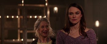 Movie still from “Collateral Beauty” (2016), directed by David Frankel – Two women standing next to each other in front of lights; Close Up shot, Over the shoulder angle